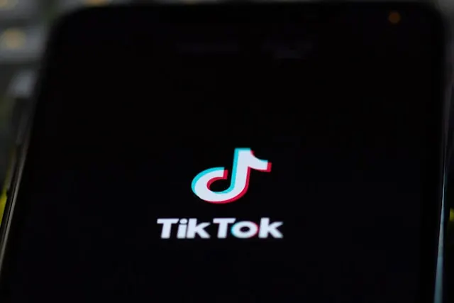 Close-up of the TikTok application logo illuminated on a smartphone screen in a dark setting.
