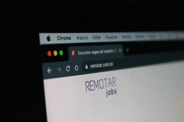 A close-up, angled shot of a laptop screen displaying a web browser. The website "remotar.com.br" is open, showing the "REMOTAR jobs" logo in the center of the page. The browser tab is in Portuguese and says "Encontre vagas de tra..." (Find jobs).